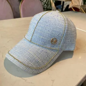 Detail of light blue tweed baseball cap with gold bead chain and M metal logo