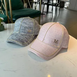Close-up of pink and grey tweed baseball caps with metal chains and M logo detail