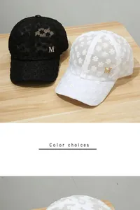 Details von Spitzen-Baseballkappen mit Blumenmuster und goldenem M-Logo in Schwarz-Weiß