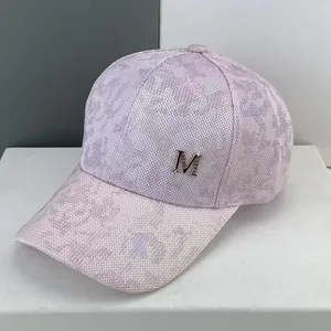 Detailed close-up of breathable mesh fabric and golden metal M logo on the pink cap
