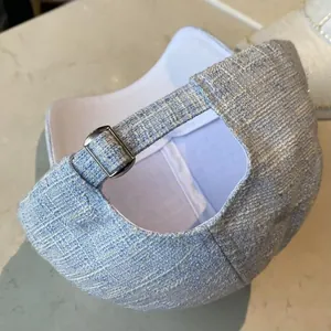 Detail of tweed baseball cap showing light blue woven texture and metal buckle
