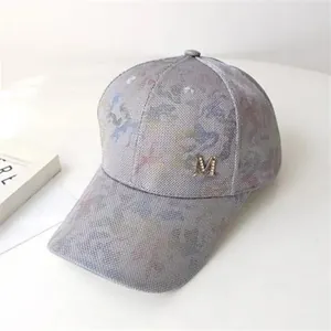 Detailed view of the camouflage baseball cap with rhinestone studded metal M logo