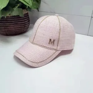 Detailed texture of pink tweed baseball cap featuring a golden metallic M logo