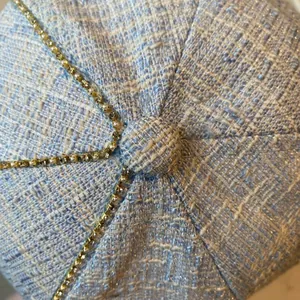 Detailed close-up of light blue tweed baseball cap with gold chains, pearls and rhinestones