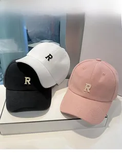 Trois casquettes de baseball brodées en noir, blanc et rose présentées sur un socle
