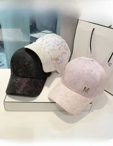 Detailed shot of camouflage baseball caps in black, white, and pink with metal M logo