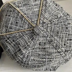 Top view detail of tweed newsboy cap with golden chain stripes and woven texture