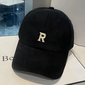 Détail de la broderie dorée de la lettre R sur une casquette de baseball noire