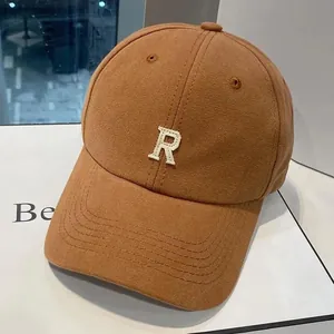 Gros plan sur la lettre R brodée en 3D blanche sur une casquette en coton orange-brun