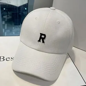 Détail de la casquette de baseball en toile blanche avec lettre R brodée noire et texture