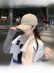 Gros plan sur casquette beige en fausse fourrure avec broderie M et écharpe en peluche