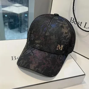 Classic baseball cap featuring a dark textured pattern and a golden metal M emblem