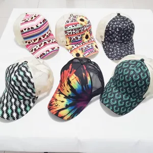 Flat lay of multiple printed ponytail trucker hats with breathable mesh and tie-dye patterns