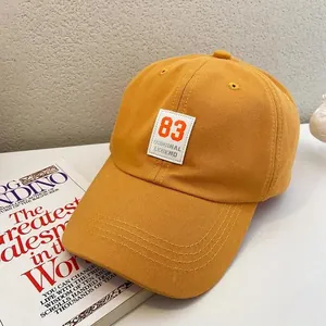 Detail of ginger cotton baseball cap showing number 83 patch and reinforced stitching