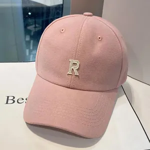 Détail d'une casquette en toile de coton rose avec écusson brodé lettre R blanche