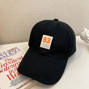 Close-up of black cotton baseball cap with orange number 83 patch and curved brim