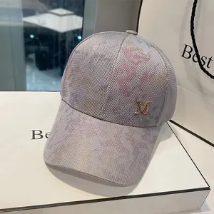 Close-up of metallic M logo on light gray mesh baseball cap with subtle colorful dye effect