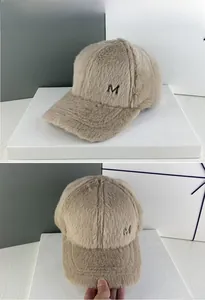 Détail de la casquette de baseball en fausse fourrure beige avec broderie de lettre M