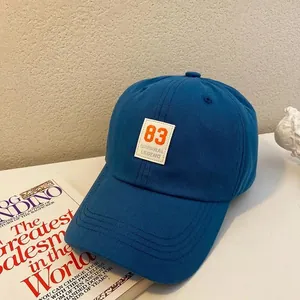 Detail of navy blue cotton baseball cap featuring orange 83 patch and curved brim