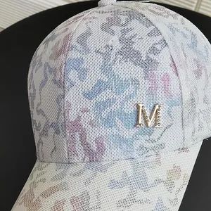 Detailed close-up of white baseball cap with colorful abstract mesh and golden M rhinestone logo