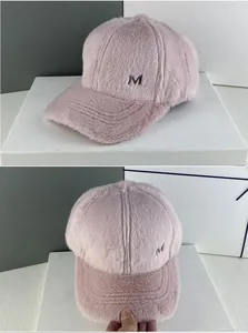 Vue détaillée de la texture en fausse fourrure rose et du logo M en métal sur la casquette