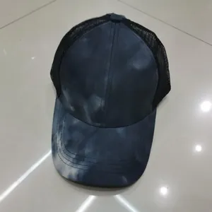 Dettaglio del cappello trucker tie-dye con pannelli blu e rete nera traspirante sul retro