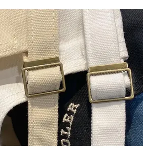 Détail de la boucle métallique réglable et de la casquette en toile brodée