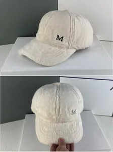 Détail d'une casquette blanche en peluche avec logo M argenté et texture douce