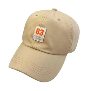 Beige cotton baseball cap featuring a vintage style number 83 patch with a curved brim