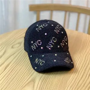 Detail of black plush baseball cap with colorful NYC rhinestone embellishments on wood