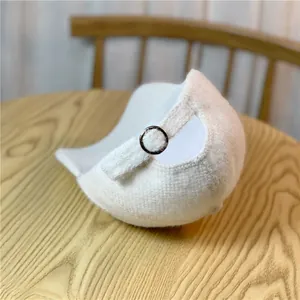 Detail of white plush baseball cap featuring a silver metal ring adjustment buckle