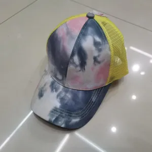 Dettaglio del tessuto tie-dye rosa e rete traspirante gialla su un cappellino trucker
