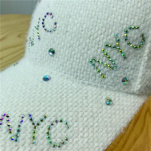 Close-up of white plush baseball cap featuring colorful rhinestone NYC lettering detail