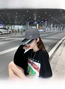 Vue lifestyle d'une casquette pied-de-poule avec visière en cuir noir et logo M doré
