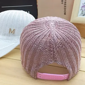 Detail of knitted mesh baseball cap with golden M logo and adjustable snapback closure