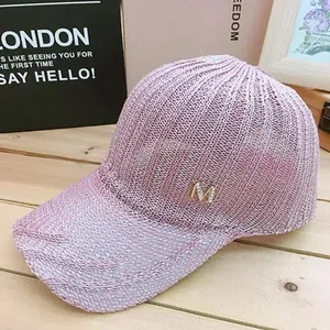 Detail of pink knitted mesh baseball cap with gold M logo and breathable texture