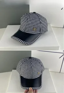 Détail de la casquette pied-de-poule avec visière en cuir noir et logo M en métal doré