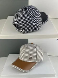 Détail de casquettes en pied-de-poule avec visières en cuir et emblèmes M en métal