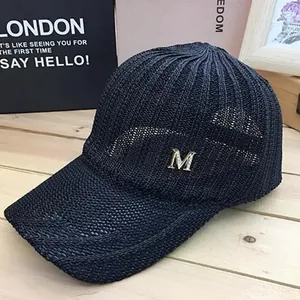 Detailed macro view of black knit mesh baseball cap featuring silver metal letter M