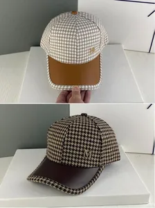 Détail de casquettes en pied-de-poule avec visières en cuir et logo M doré en métal