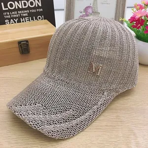 Detail of beige knitted mesh baseball cap featuring a sparkling metal M logo and texture