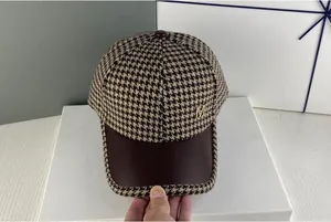 Détail du logo M en métal sur casquette pied-de-poule avec bord en cuir brun
