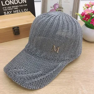 Detailed texture of grey knit baseball cap featuring a sparkling rhinestone metal M logo