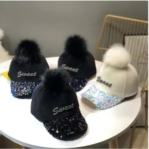 Detalle de gorras de invierno con lentejuelas, pompones de piel sintética y bordado Sweet