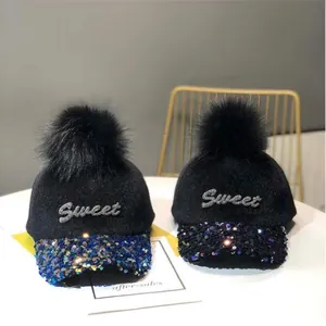 Primer plano detallado de dos gorras de lana negra con lentejuelas Sweet y pompón de piel