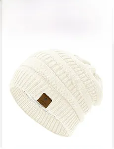 Close-up of cream knitted beanie with star leather patch and warm fleece lining