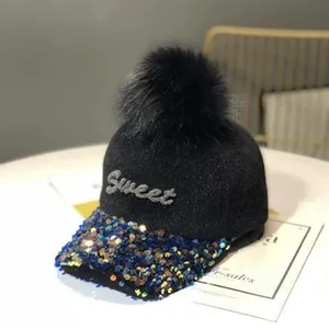 Detalle de lentejuelas azules y bordado Sweet en una gorra de invierno negra con pompón