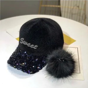 Detalle de gorra de béisbol de terciopelo negro con bordado Sweet de lentejuelas y pompón