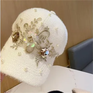 Detail einer weißen Plüsch-Baseballkappe mit Perlen und goldener Blumenstickerei