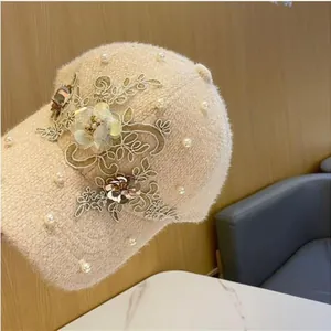 Detail der beige Plüsch-Baseballkappe mit zarten Spitze-Blumen und weißen Perlenakzenten